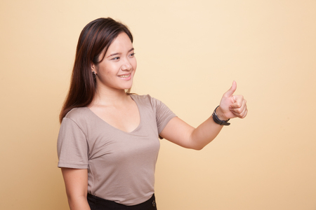 Asian woman thumbs up  and smile on beige backgroundの写真素材
