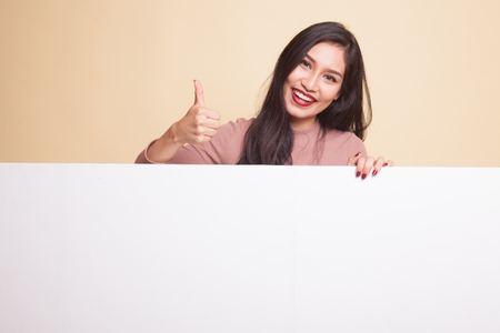 Young Asian woman show OK with blank sign on beige backgroundの写真素材