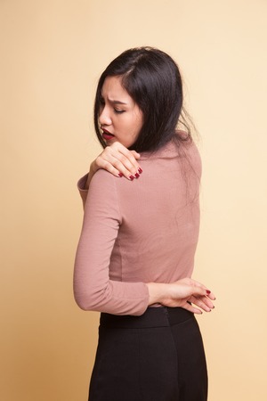 Young Asian woman got back pain on beige backgroundの写真素材