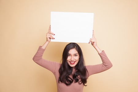 Young Asian woman with white blank sign on beige backgroundの写真素材