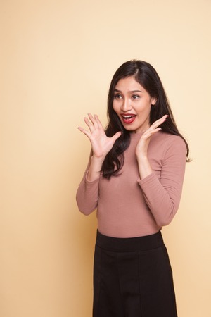 Young Asian woman is surprised and smile on beige backgroundの写真素材