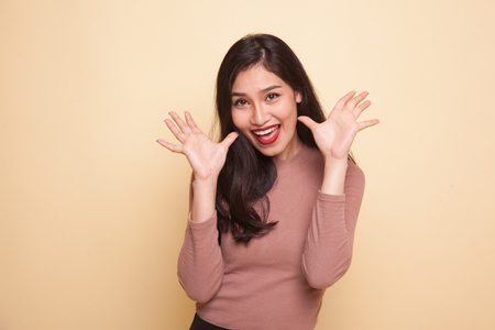 Young Asian woman sticking her  tongue out on beige backgroundの写真素材