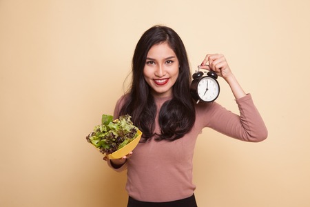 Young Asian woman with boxing glove and salad on beige backgroundの写真素材
