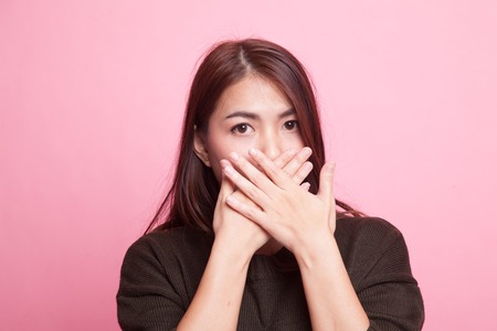 Beautiful young Asian woman close her mouth on pink backgroundの写真素材