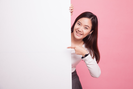 Young Asian woman point to a  blank sign on pink backgroundの写真素材