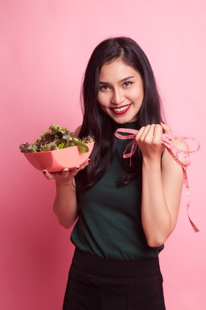 Healthy  Asian woman with measuring tape and salad on pink backgroundの写真素材