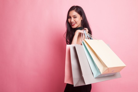 Young Asian woman happy with shopping bag on pink backgroundの写真素材