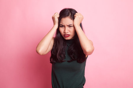 Young Asian woman got sick and  headache on pink backgroundの写真素材
