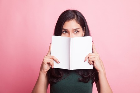 Young Asian woman with a book on pink backgroundの写真素材