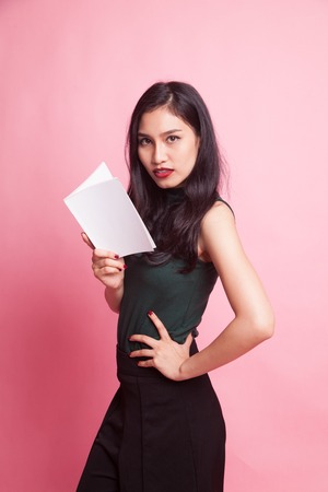 Young Asian woman read a book on pink backgroundの写真素材