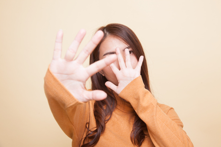 Young Asian woman hide her  face on beige backgroundの写真素材