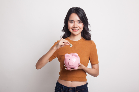 Asian woman with coin and pig coin bank on white backgroundの写真素材