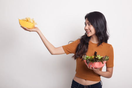 Young Asian woman with potato chips and salad on white backgroundの写真素材