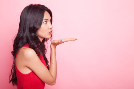 Beautiful young Asian woman blow a kiss on pink backgroundの写真素材