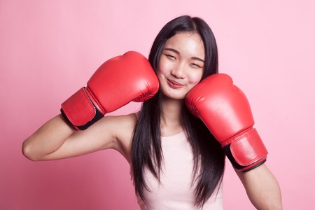Young Asian woman with red boxing gloves on pink backgroundの写真素材