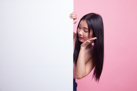 Excited young Asian woman with blank sign on pink backgroundの写真素材