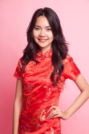 Cute Asian girl in chinese red cheongsam dress  on pink backgroundの写真素材