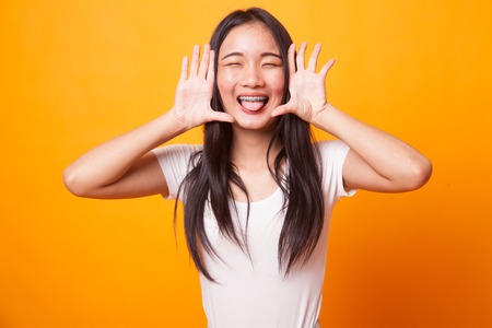 Young Asian woman sticking her  tongue out on bright yellow backgroundの写真素材