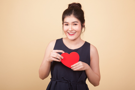 Asian woman with red heart  on beige backgroundの写真素材