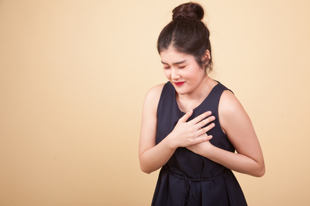 Young Asian woman got chest pain  on beige backgroundの写真素材