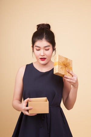 Young Asian woman open a gift box  on beige backgroundの写真素材