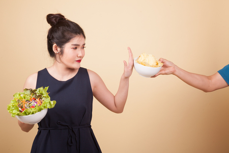 Young Asian woman eat potato chips  on beige backgroundの写真素材