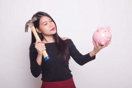 Asian woman with pig coin bank and hammer on white backgroundの写真素材