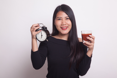 Young Asian woman with tomato juice and clock on white backgroundの写真素材