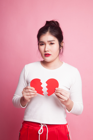 Beautiful young Asian woman with broken heart on pink backgroundの写真素材