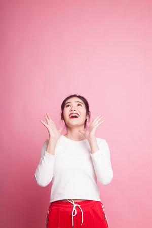 Excited young Asian woman look up on pink backgroundの写真素材