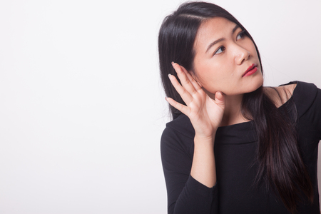 Beautiful young Asian woman listen to something on white backgroundの写真素材