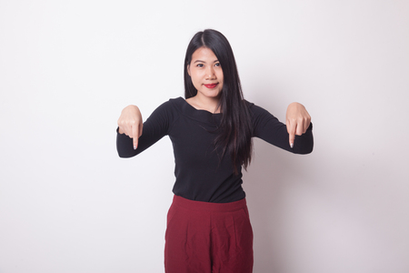 Beautiful young Asian woman point down to blank space on white backgroundの写真素材