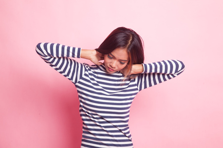Sleepy young Asian woman yawn on pink backgroundの写真素材