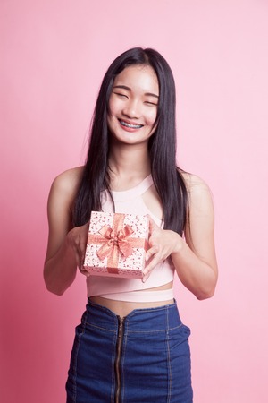 Young Asian woman with a gift box on pink backgroundの写真素材