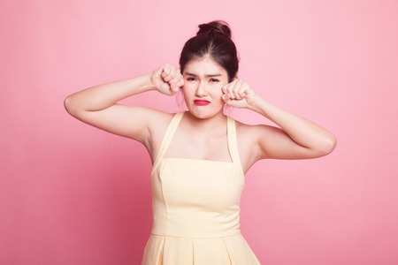 Young Asian woman sad and cry on pink backgroundの写真素材