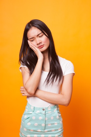 Beautiful young Asian woman get bored on bright yellow background