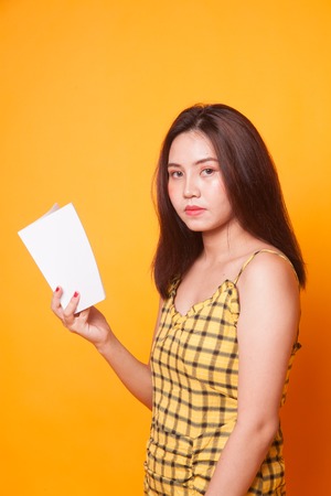 Young Asian woman read a book on yellow backgroundの写真素材