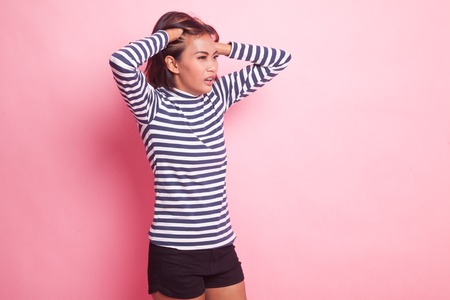 Stressed young Asian businesswoman scream out on pink backgroundの写真素材