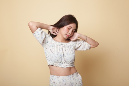 Sleepy young Asian woman yawn on beige backgroundの写真素材