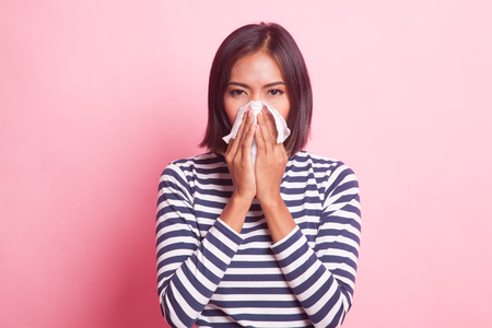Young Asian woman got sick and flu on pink backgroundの写真素材