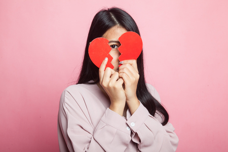 Beautiful young Asian woman with broken heart on pink backgroundの写真素材