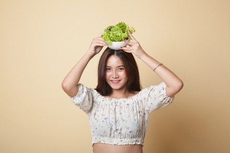 Healthy Asian woman with salad on beige backgroundの写真素材