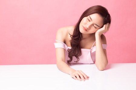 Asian girl is getting bore on pink backgroundの写真素材