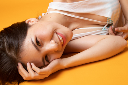 Portrait of beautiful  sexy young Asian woman on yellow backgroundの写真素材