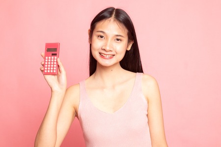 Asian woman smile with calculator on pink backgroundの写真素材