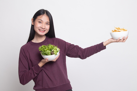 Young Asian woman with potato chips and salad on white backgroundの写真素材