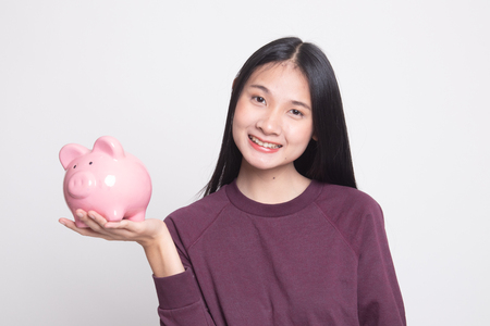 Young Asian woman with a pig coin bank on white backgroundの写真素材