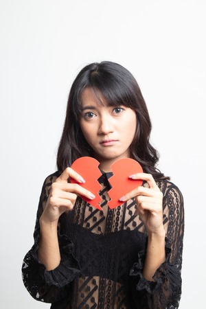 Beautiful young Asian woman with broken heart on white background