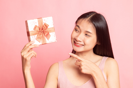 Young Asian woman with a gift box on pink backgroundの写真素材