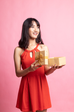 Young Asian woman open a gift box on pink backgroundの写真素材